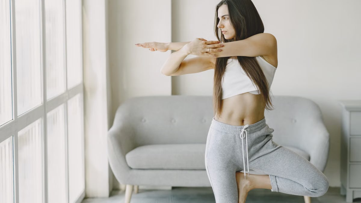 A woman performs a yoga pose at home, focusing on balance and tranquility.